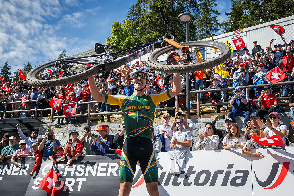 South Africa's Alan Hatherly holds up his bicycle to celebrate winning in the Men's elite Cross-country Olympic race as part of the 2025 UCI Mountain Bike World Championships in Crans-Montana on September 14, 2025.